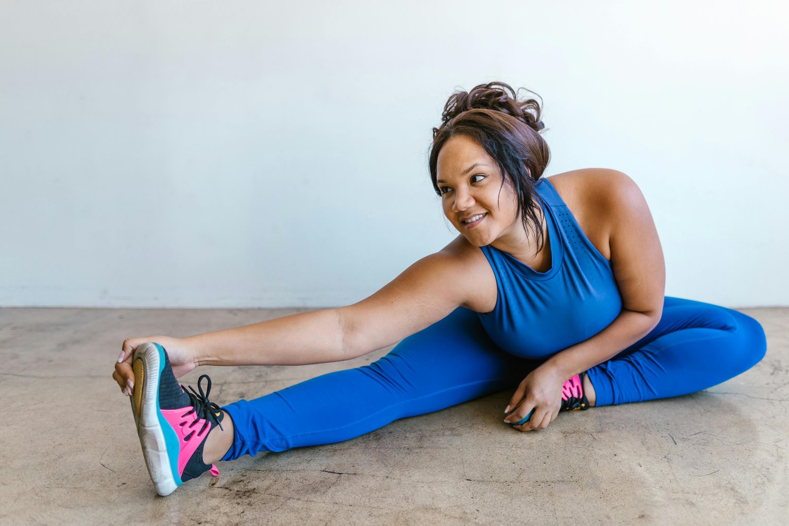 A Lady Sitting on the Floor Stretching Her Body in Exercise 